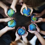 Group of diverse kids hands holding cupping globe balls together