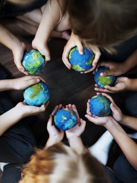 Group of diverse kids hands holding cupping globe balls together